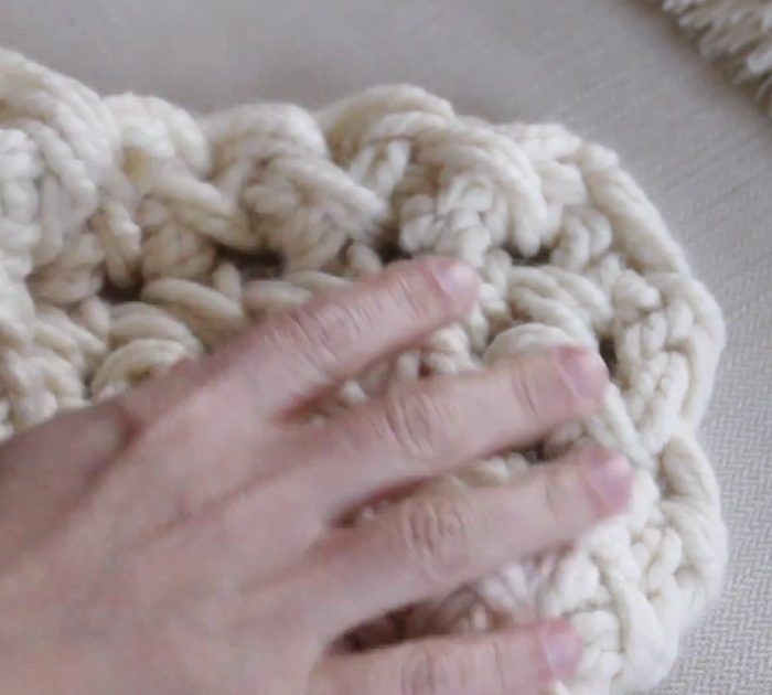 Woman shows simple way to hand crochet a chunky blanket in