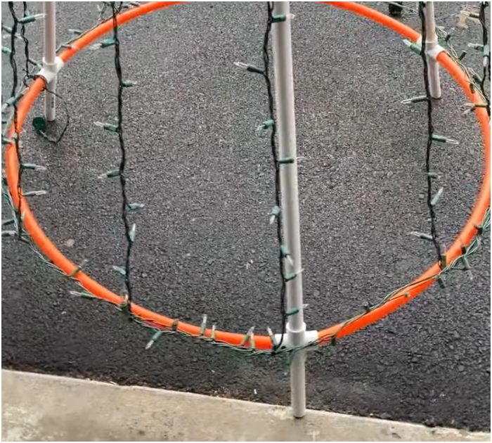 Man stacks hula hoops over teepee made of PVC pipes for a different take on Christmas tree