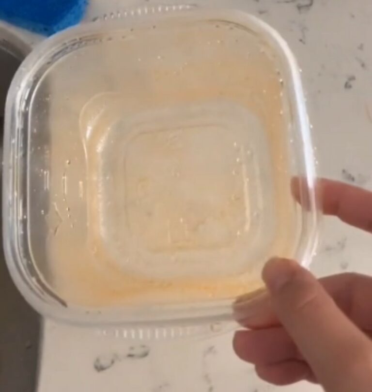 Young woman shows how to get grease stains out of Tupperware with
