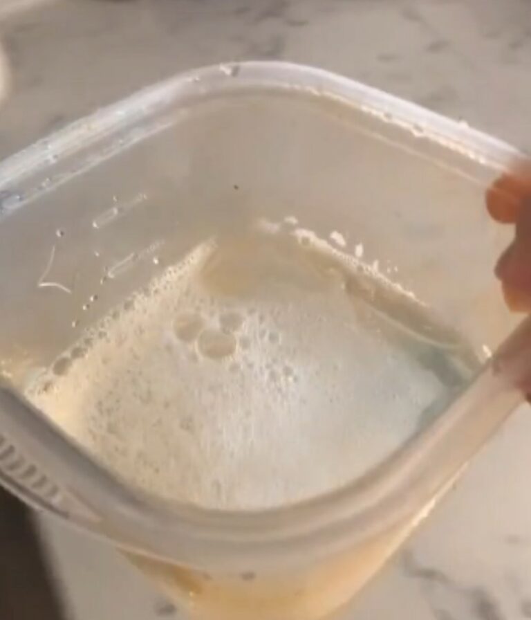 Young woman shows how to get grease stains out of Tupperware with