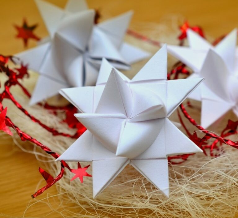Woman folds up 4 thin strips of paper and weaves them together to make ...